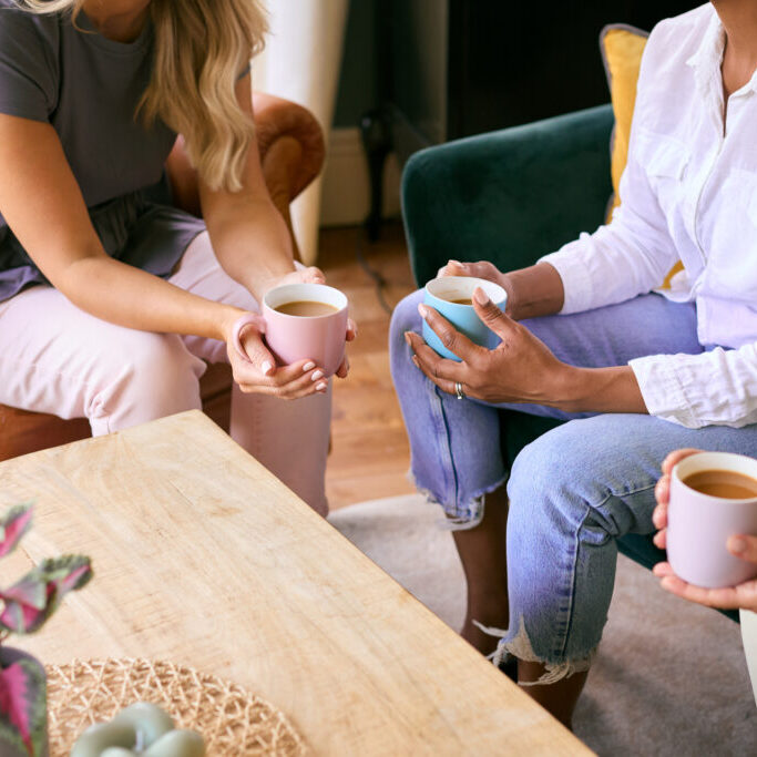 Close Up Of Three Mature Female Friends In Lounge At Home Meeting For A Chat And Hot Drink