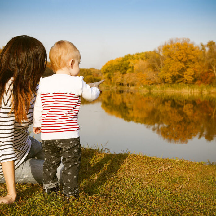 Happy mother and her baby on autumn lake